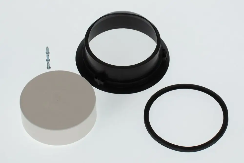 BOSCH Lufteinlassadapter, bestehend aus drei Teilen: einem schwarzen Ring mit Durchlass, einem weißen Deckel und einem schwarzen Dichtsatz. Schrauben im Hintergrund.